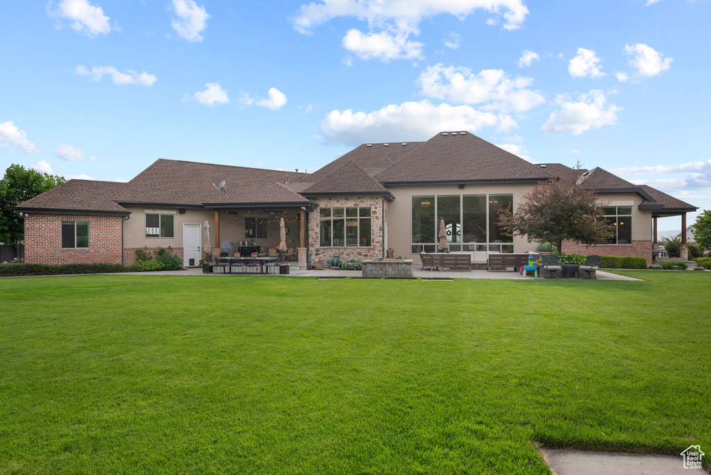 Rear view of house with a patio area, a lawn, outdoor lounge area, and brick siding