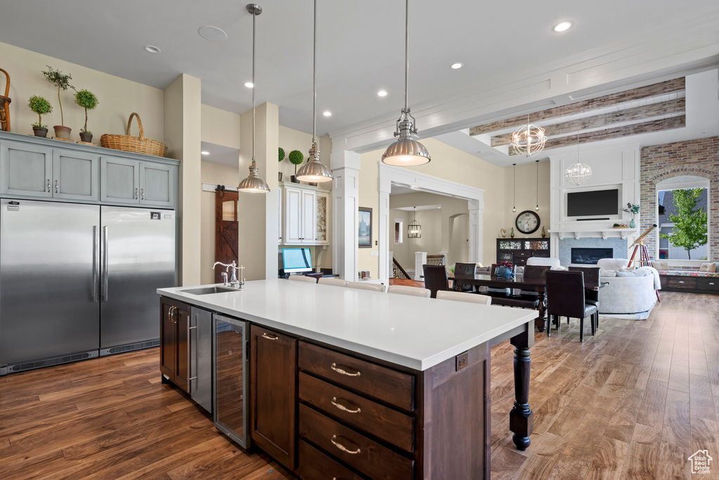 Kitchen with built in fridge, open floor plan, wine cooler, dark wood finished floors, and light countertops