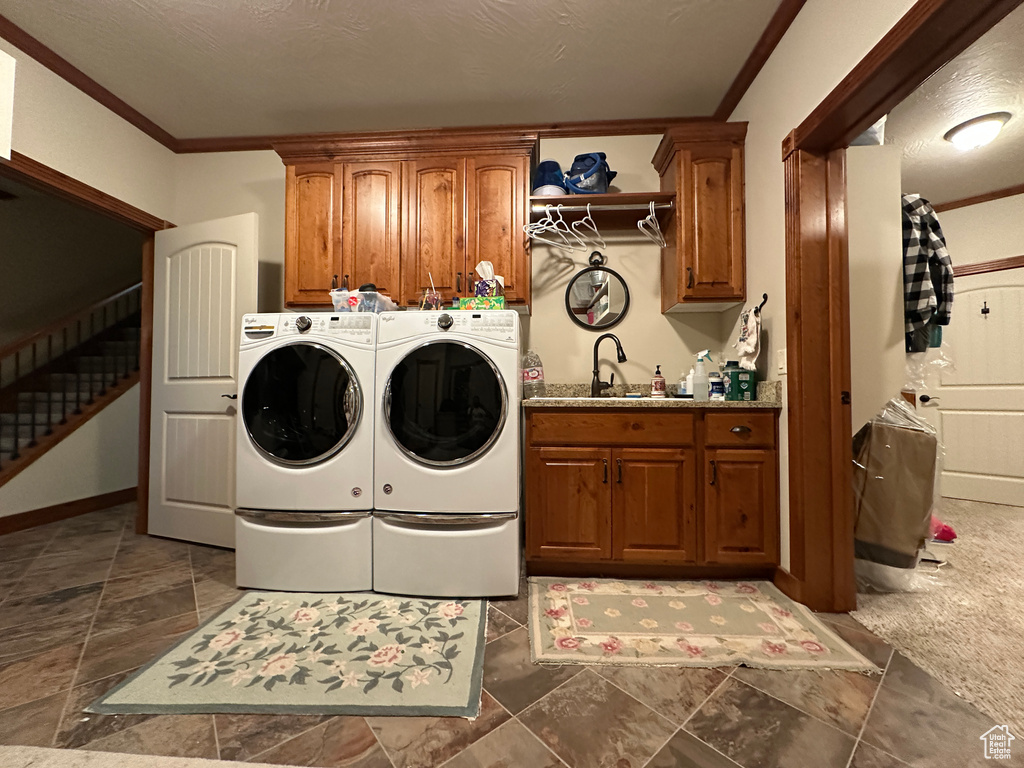 Washroom with cabinet space, ornamental molding, and washer and clothes dryer