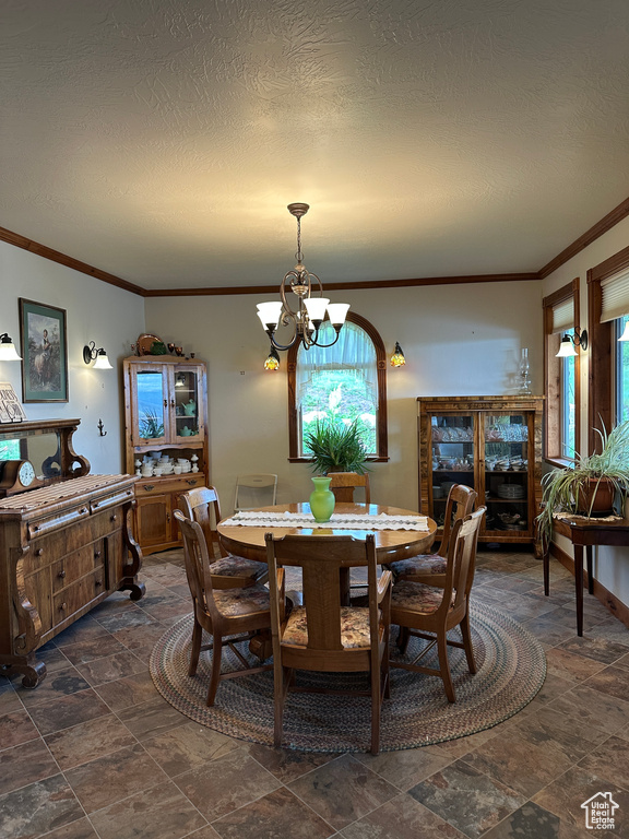 Dining space featuring a chandelier, crown molding, dark stone finish floors, and a textured ceiling