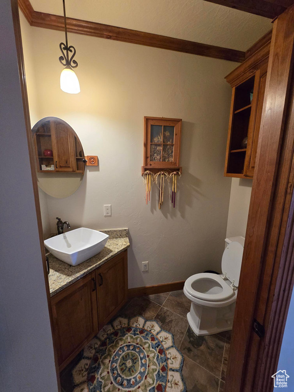 Half bathroom with vanity, crown molding, toilet, baseboards, and tile patterned floors