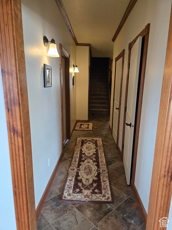 Corridor with crown molding, baseboards, and stone finish flooring