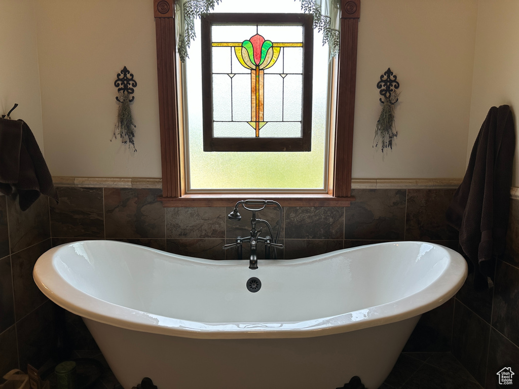 Full bath featuring a soaking tub, tile walls, and wainscoting