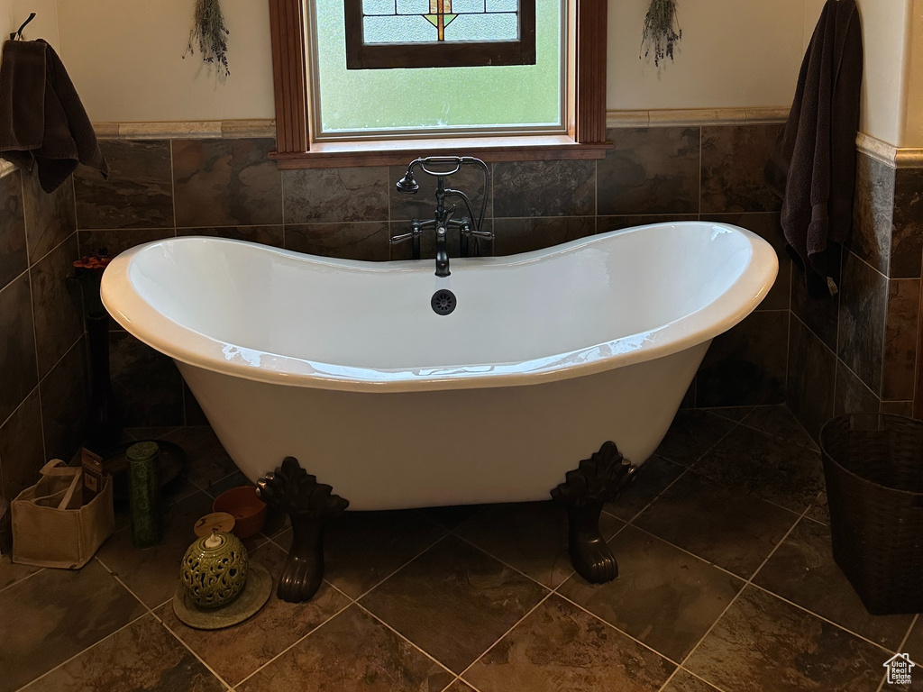 Full bath with tile walls, a wainscoted wall, a freestanding bath, crown molding, and tile patterned flooring