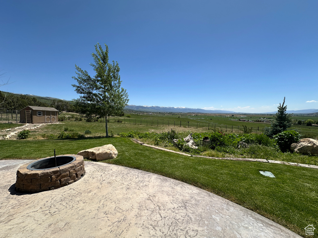 View of yard with an outdoor fire pit, a patio, a mountain view, and a view of countryside