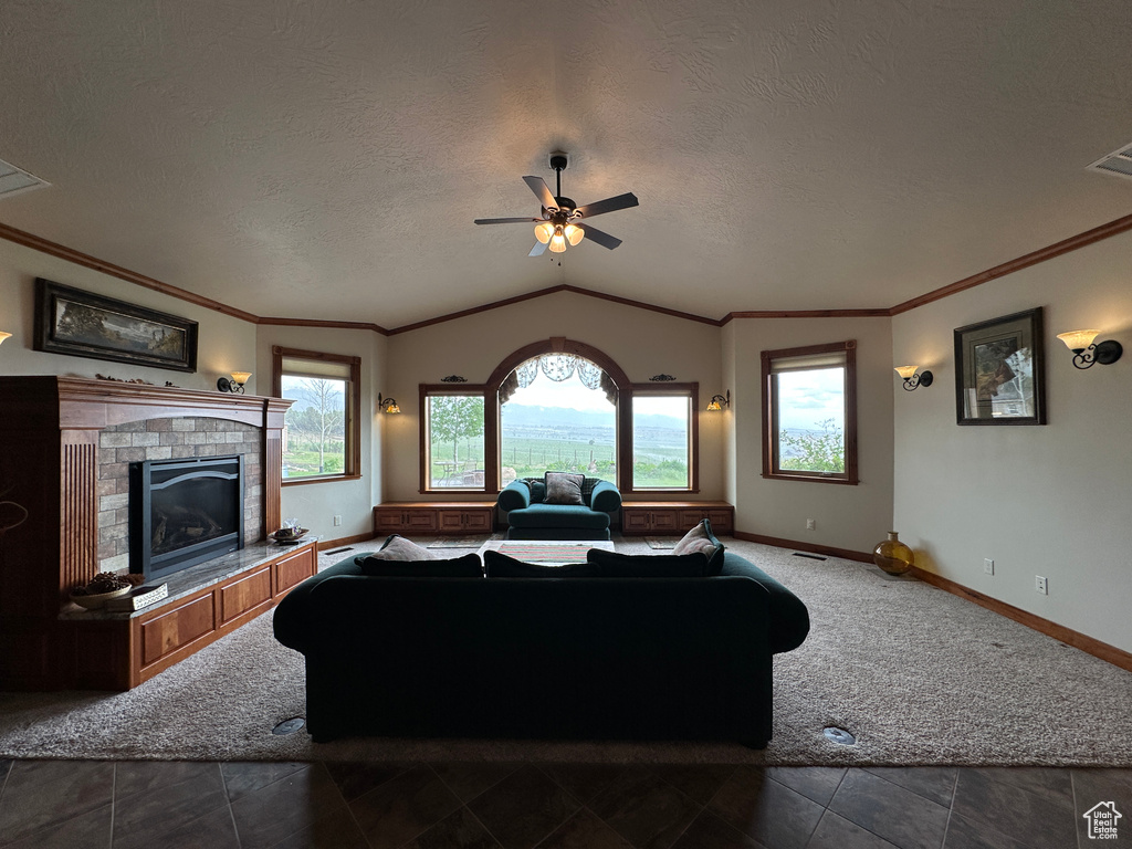 Living area featuring vaulted ceiling, ceiling fan, a textured ceiling, baseboards, and a brick fireplace
