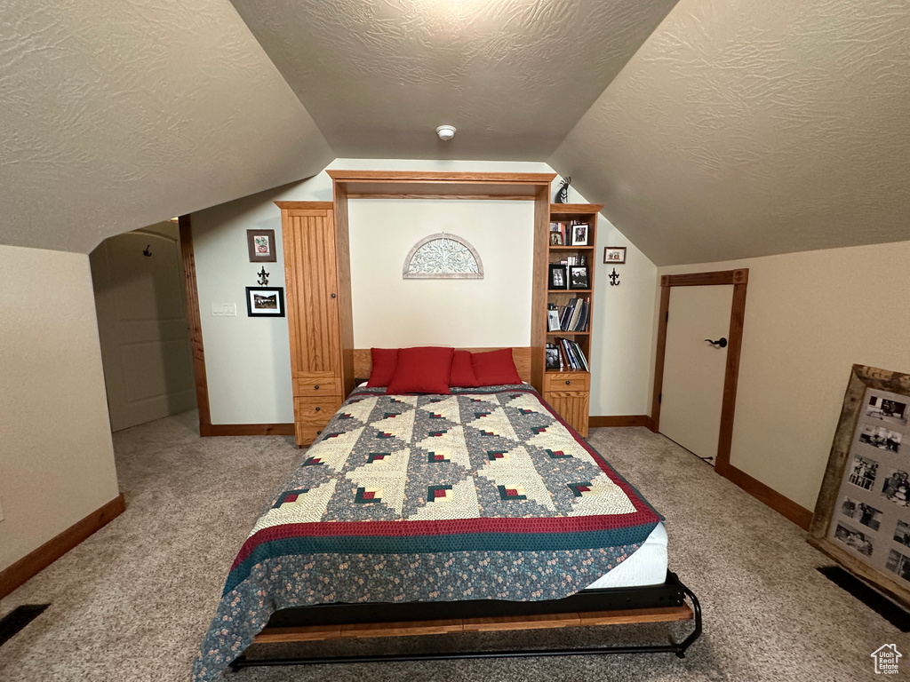 Bedroom with a textured ceiling, baseboards, carpet floors, and vaulted ceiling