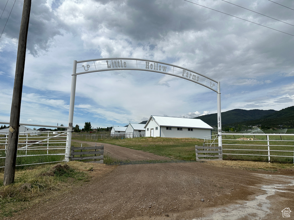 View of dirt / gravel driveway featuring a view of countryside, a mountain view, and a gated entry
