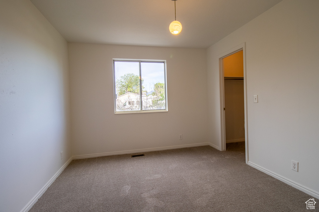 Unfurnished bedroom featuring carpet floors, a walk in closet, baseboards, and a closet