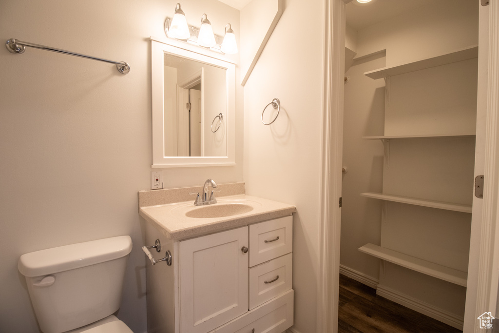 Half bathroom featuring toilet, vanity, and wood finished floors