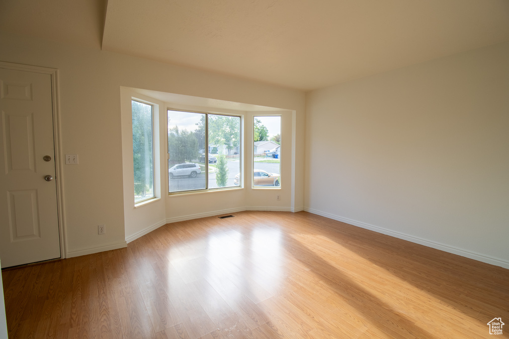 Spare room featuring light wood-style flooring and baseboards