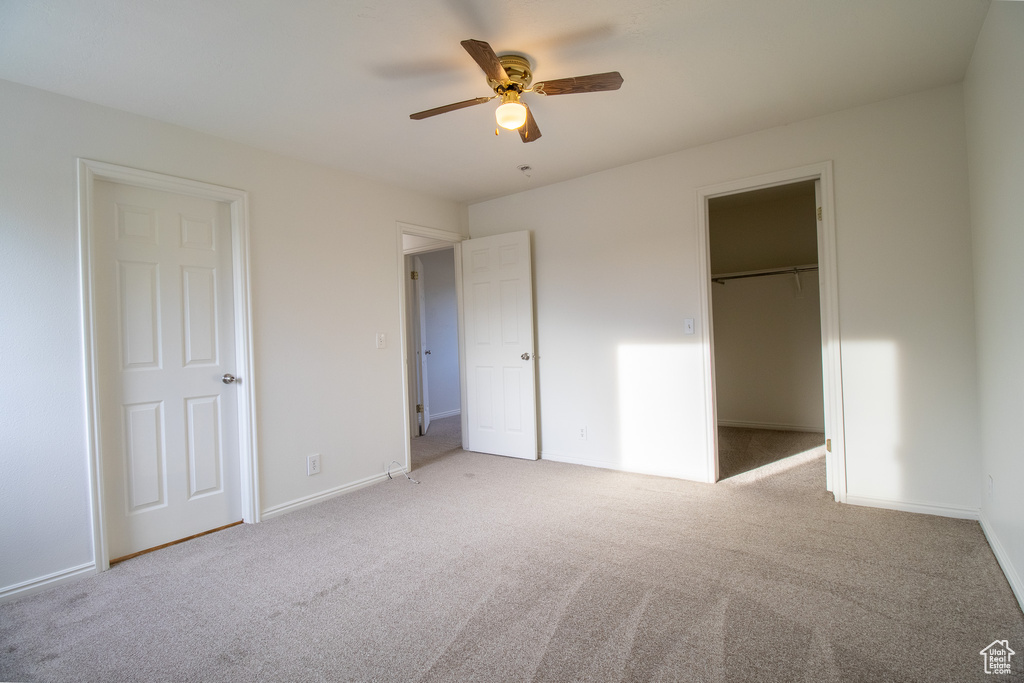 Unfurnished bedroom with carpet floors, a spacious closet, and baseboards