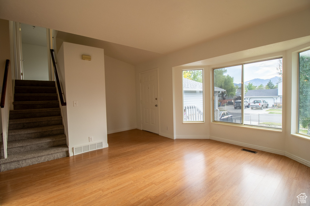 Unfurnished room featuring light wood-style flooring, stairway, baseboards, and a mountain view