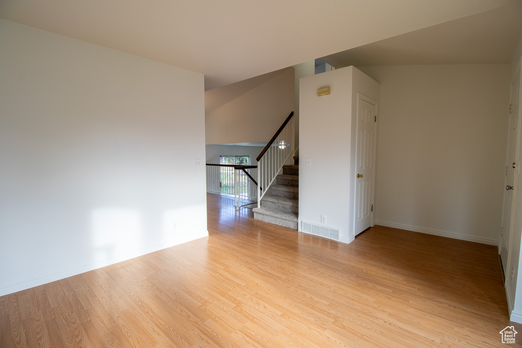 Unfurnished room with wood finished floors, stairway, and baseboards