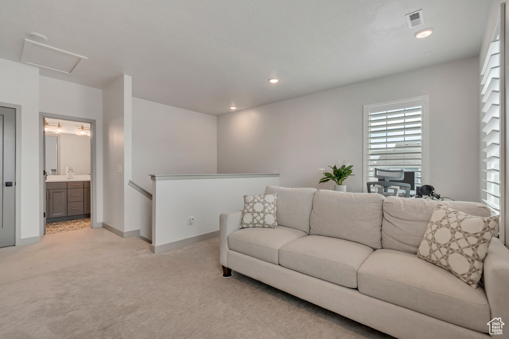 Living area featuring light colored carpet, attic access, and recessed lighting