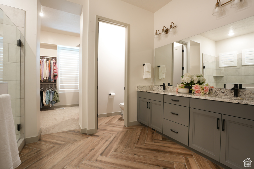 Bathroom featuring double vanity, tiled shower, and a walk in closet