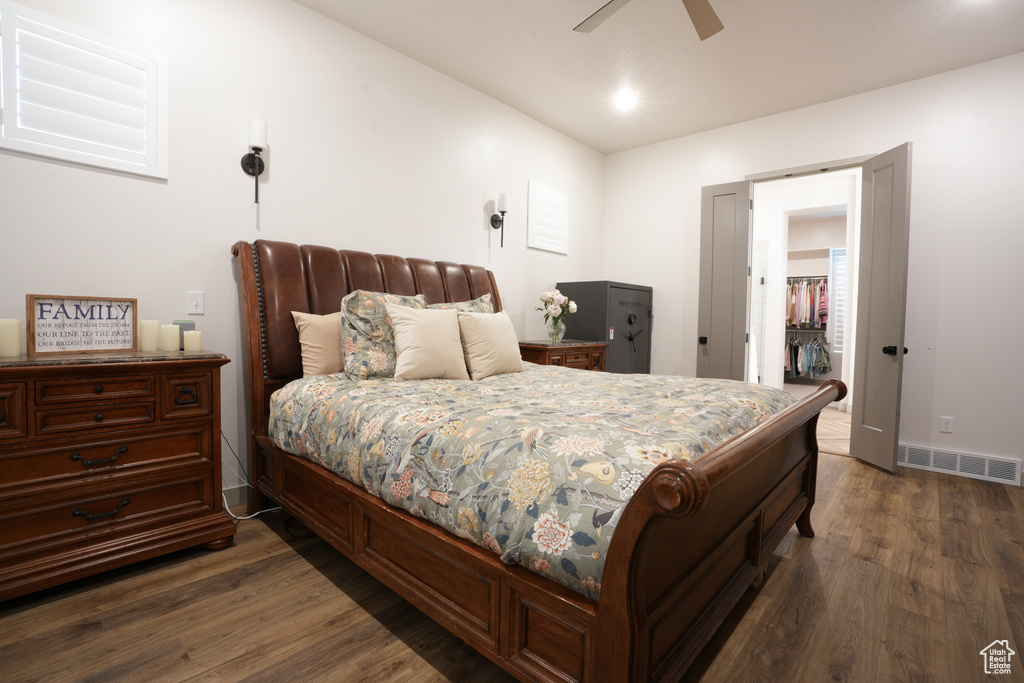 Bedroom with dark wood-style floors, a ceiling fan, and a walk in closet