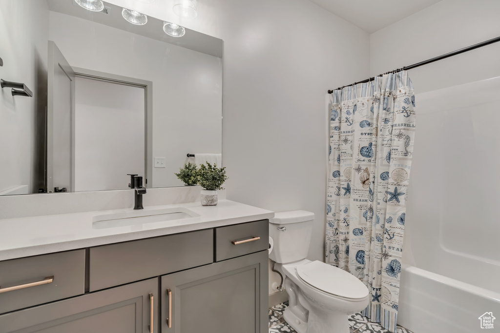 Full bath with vanity, shower / bath combo with shower curtain, and tile patterned floors