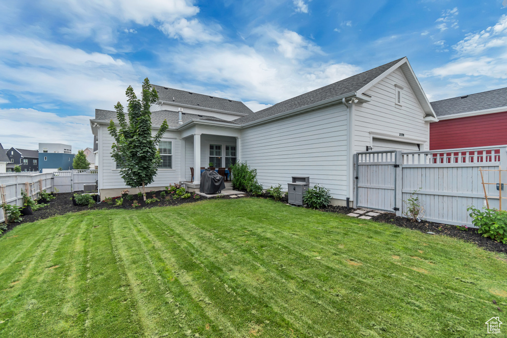 Back of property featuring an attached garage, a fenced backyard, a gate, and a shingled roof