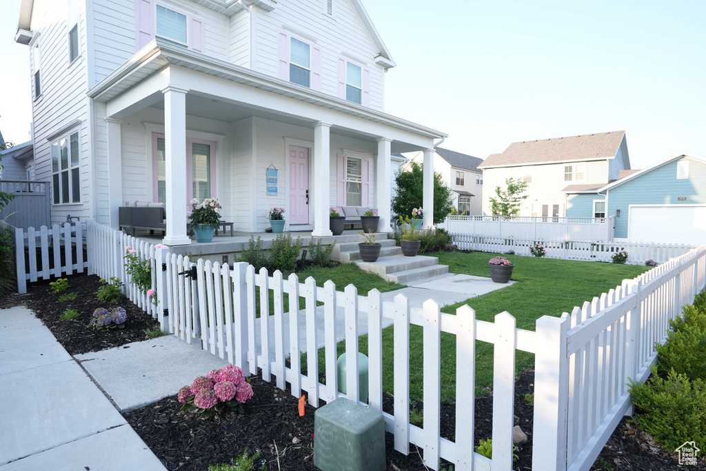 View of front facade with a porch, a garage, and a fenced front yard