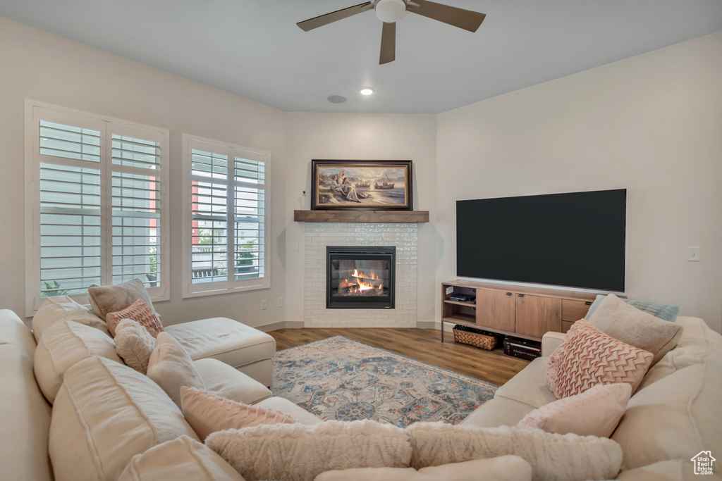 Living area featuring a ceiling fan, recessed lighting, a glass covered fireplace, and wood finished floors