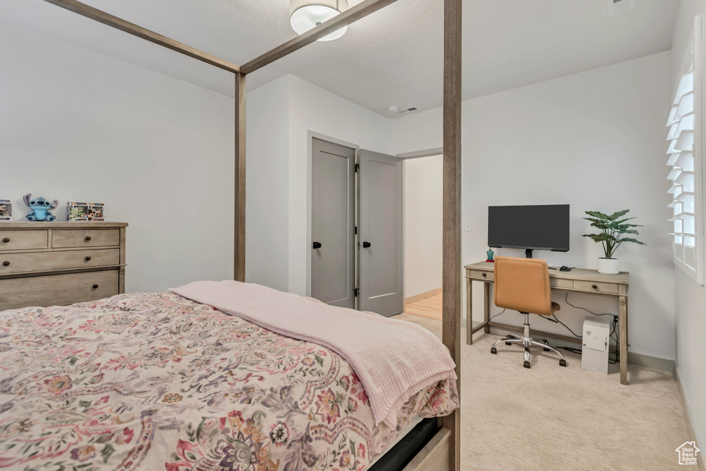 Bedroom with light colored carpet and an office area