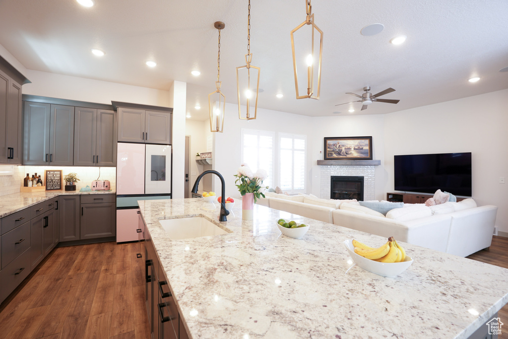 Kitchen featuring a sink, a ceiling fan, gray cabinetry, a glass covered fireplace, and recessed lighting