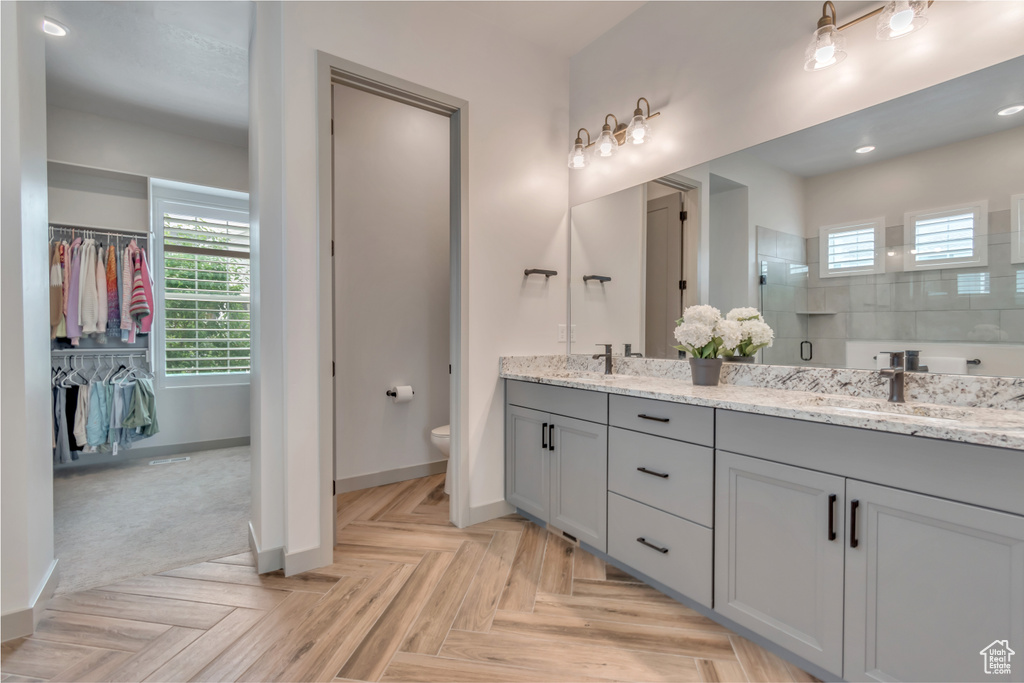 Full bathroom featuring double vanity, healthy amount of natural light, a walk in shower, a walk in closet, and recessed lighting