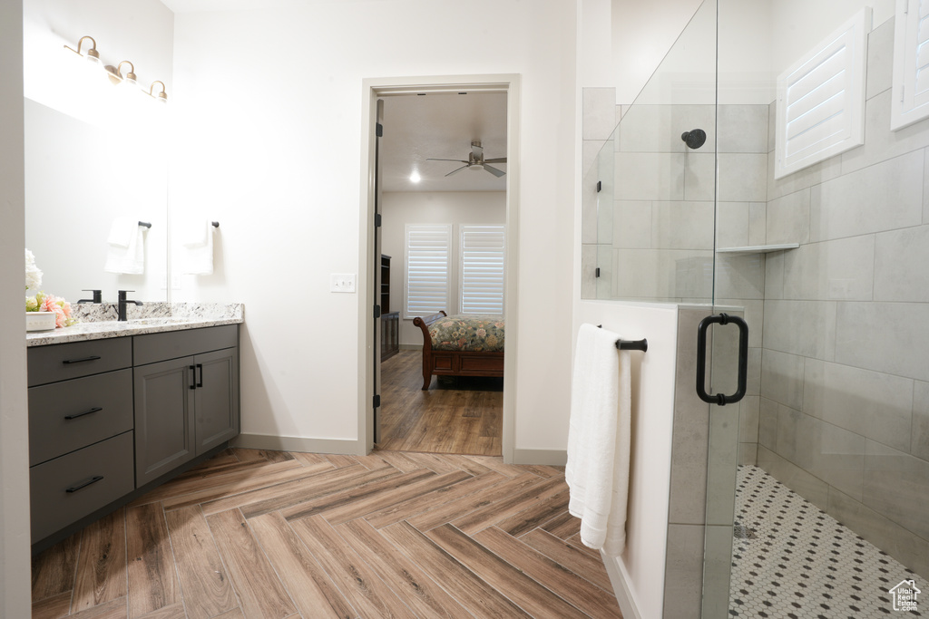 Ensuite bathroom featuring vanity, a shower stall, and ceiling fan