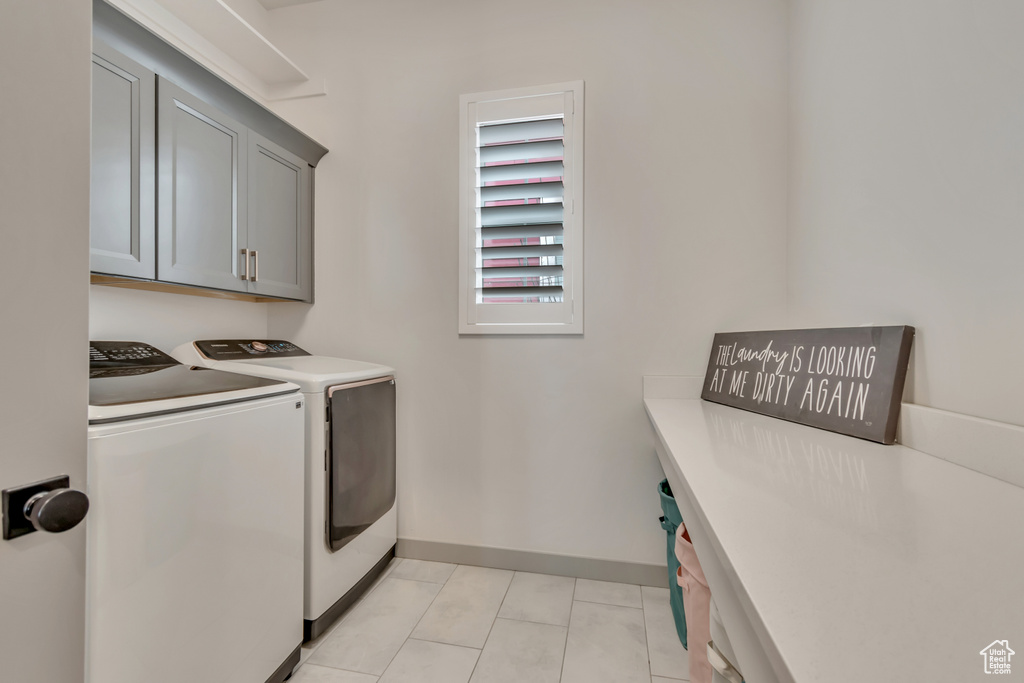Washroom featuring cabinet space, washing machine and clothes dryer, and light tile patterned floors