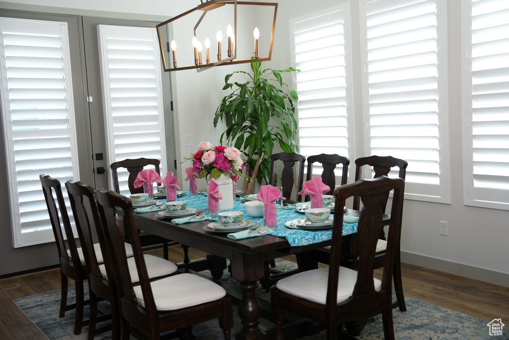 Dining area with a chandelier, wood finished floors, and baseboards