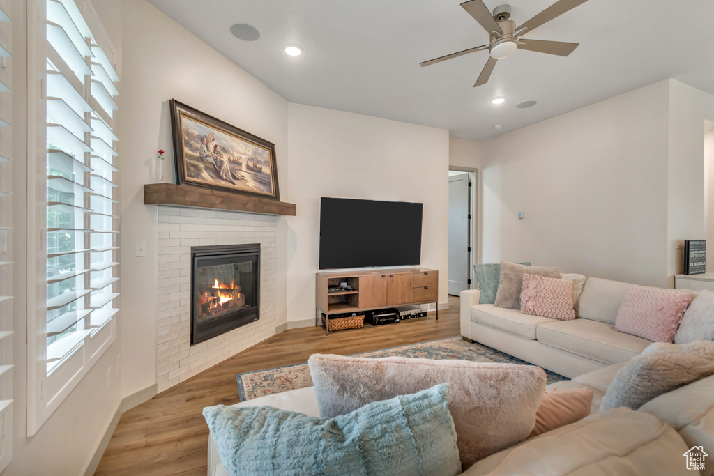 Living room featuring a ceiling fan, light wood finished floors, a fireplace, and recessed lighting