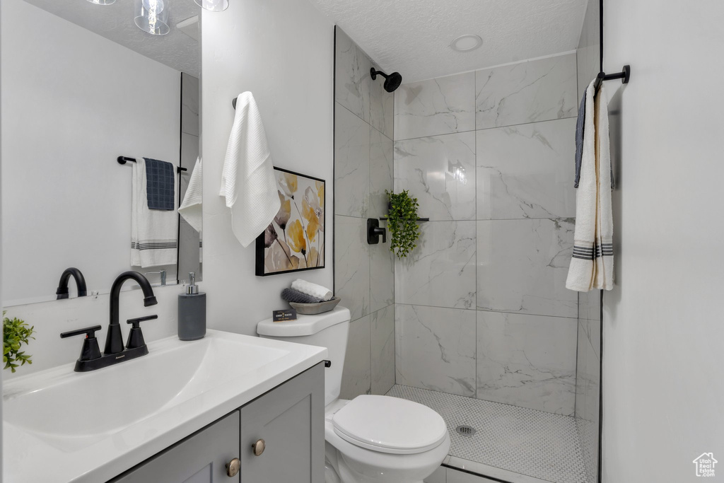 Bathroom with vanity, a marble finish shower, toilet, and a textured ceiling
