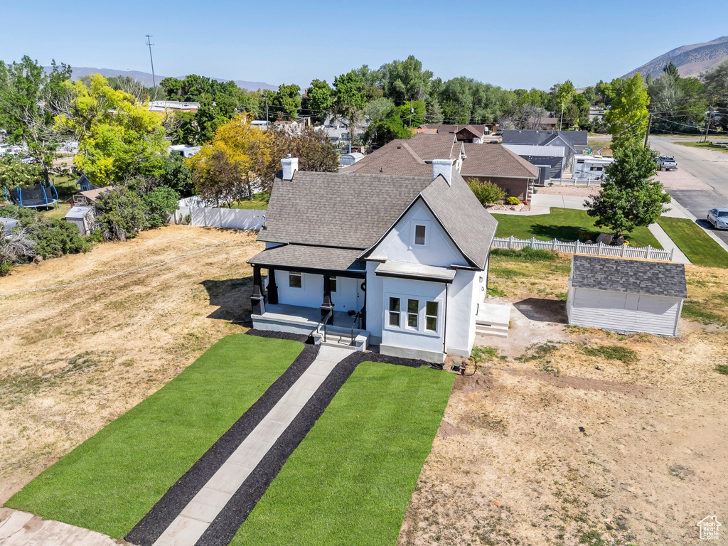 View of front of house featuring a shingled roof, a porch, stucco siding, a mountain view, and an outdoor structure