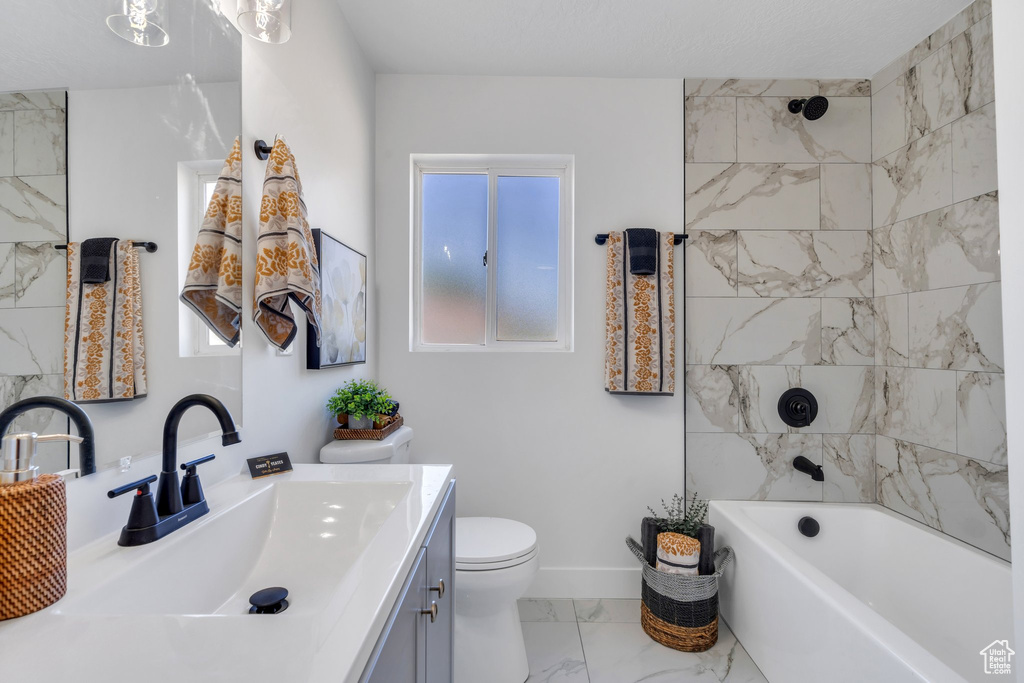 Bathroom with marble look tile flooring, vanity, toilet, baseboards, and shower / bathtub combination