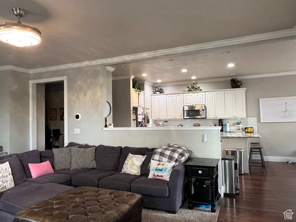 Living area with dark wood finished floors, recessed lighting, crown molding, and baseboards