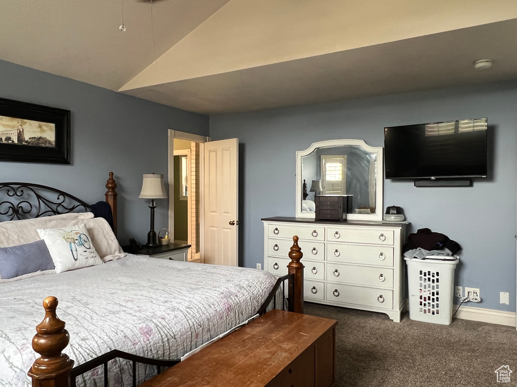 Carpeted bedroom with vaulted ceiling and baseboards