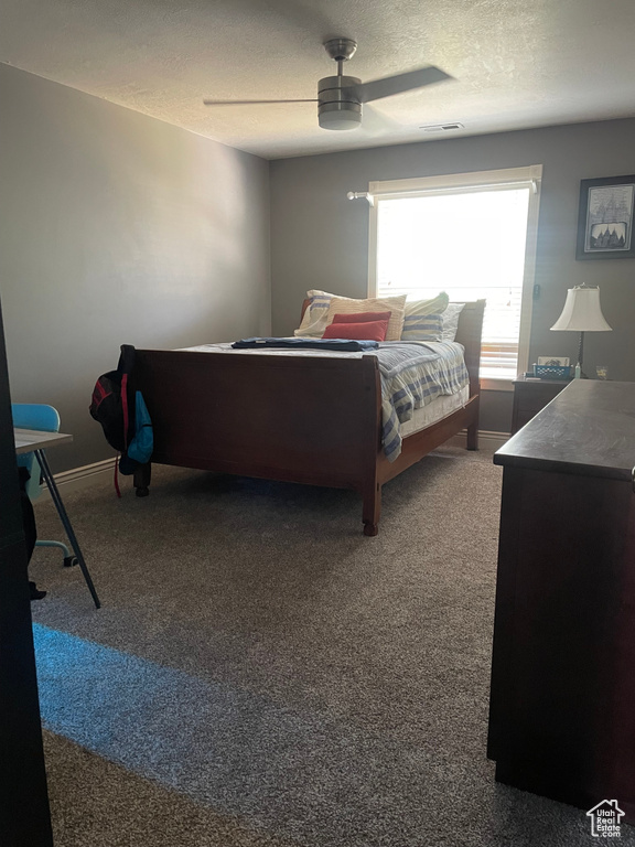 Carpeted bedroom with a textured ceiling, a ceiling fan, and baseboards