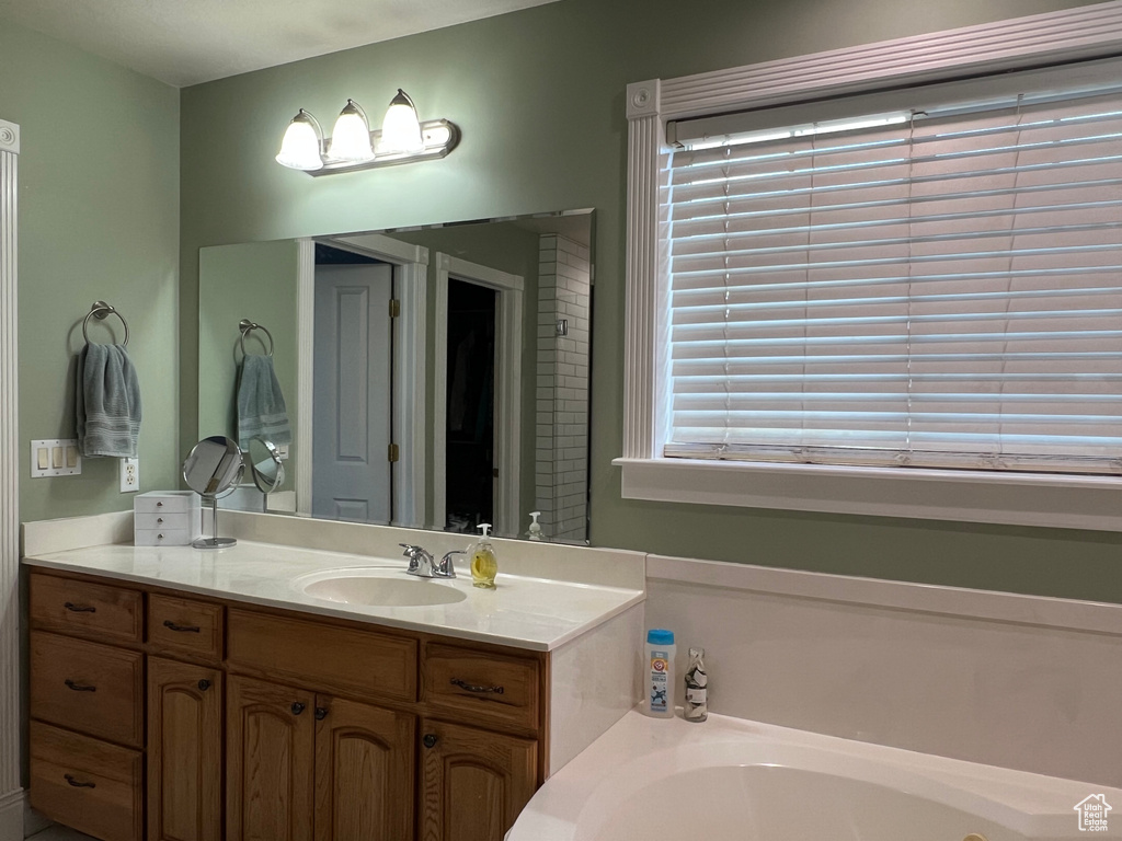Full bathroom featuring a garden tub, vanity, and plenty of natural light