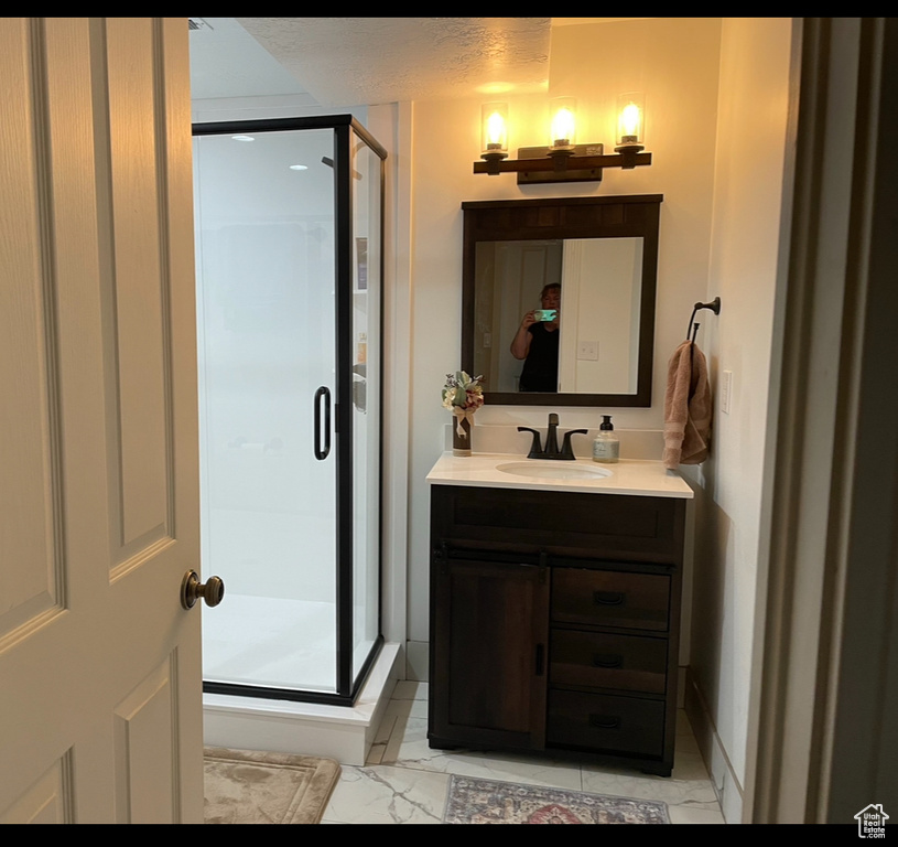 Bathroom featuring vanity, a shower stall, and marble finish floors