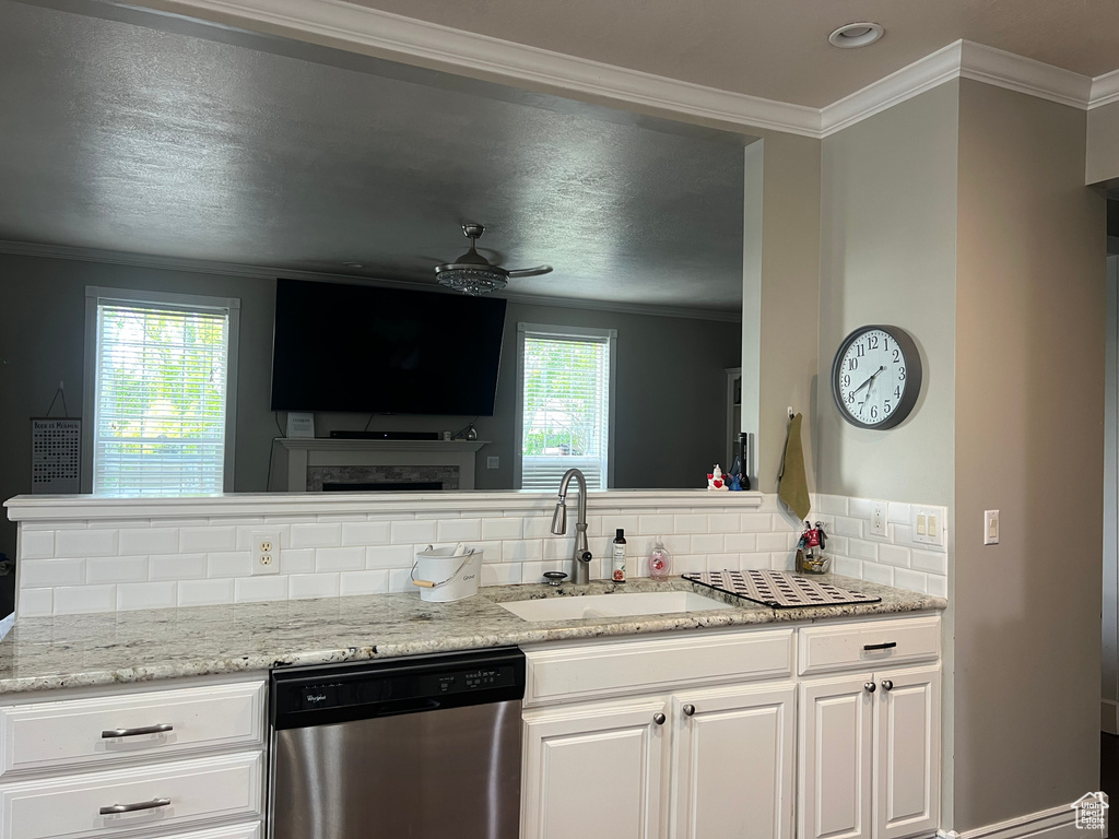 Kitchen featuring dishwasher, a sink, decorative backsplash, ceiling fan, and white cabinetry