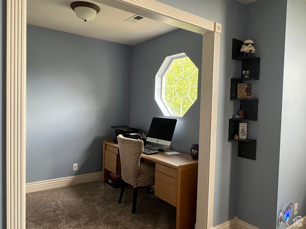 Home office featuring dark colored carpet and baseboards