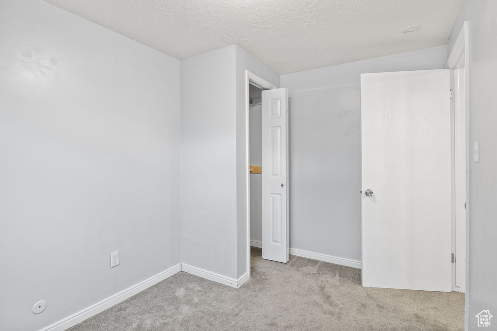 Unfurnished bedroom featuring carpet, baseboards, and a textured ceiling