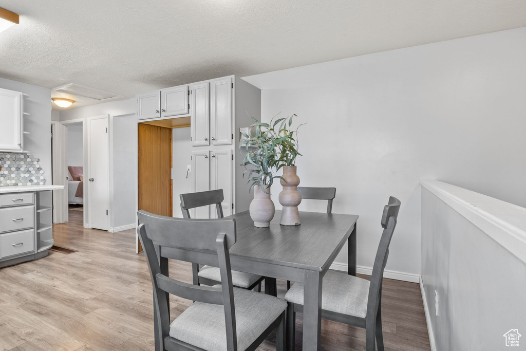 Dining room featuring light wood-style floors, baseboards, and a textured ceiling