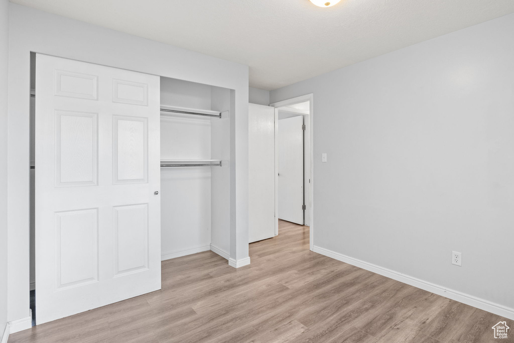 Unfurnished bedroom with light wood-type flooring, a closet, and baseboards