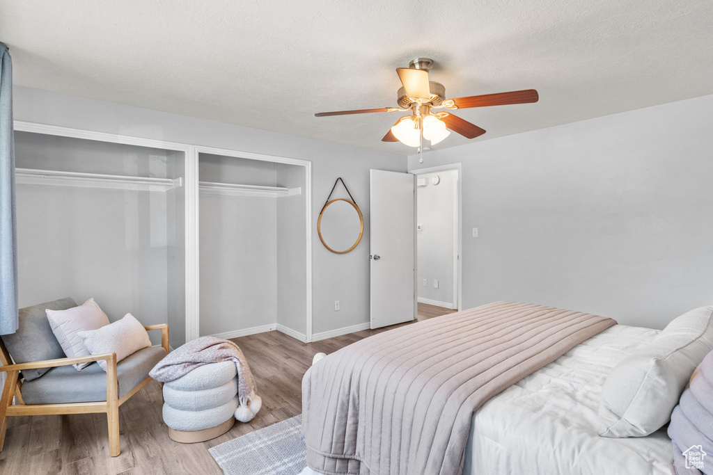 Bedroom with wood finished floors, ceiling fan, baseboards, and a closet