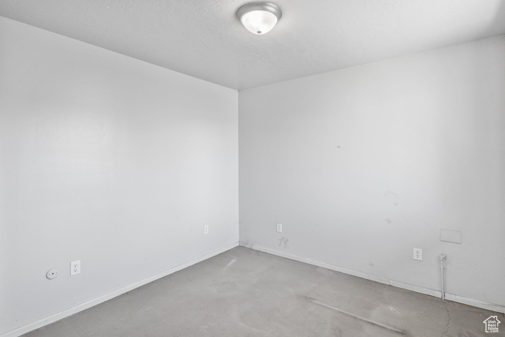 Unfurnished room with concrete flooring and baseboards