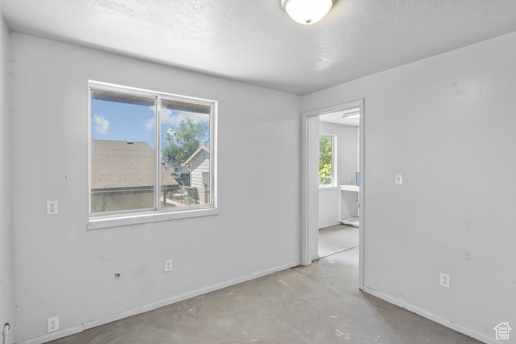 Empty room featuring baseboards, a textured ceiling, and concrete floors