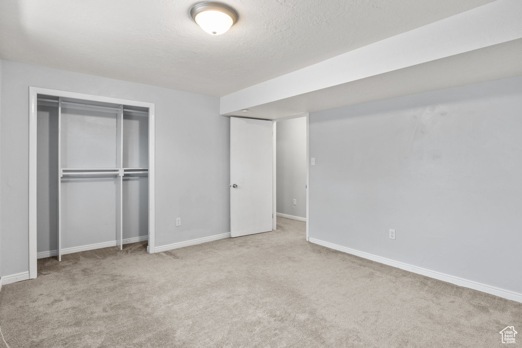 Unfurnished bedroom with a textured ceiling, carpet flooring, baseboards, and a closet