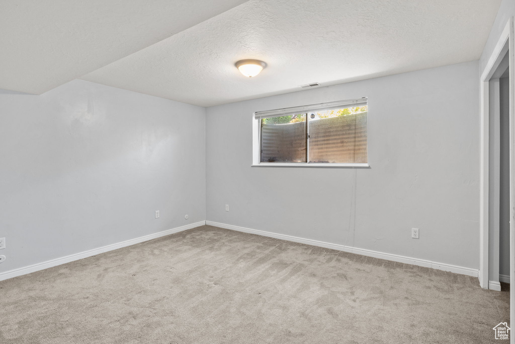 Spare room featuring carpet floors, baseboards, and a textured ceiling